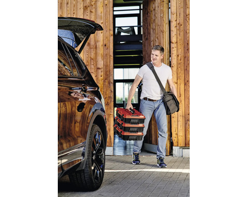 Un homme transporte trois boîtes à outils jusqu''à la voiture