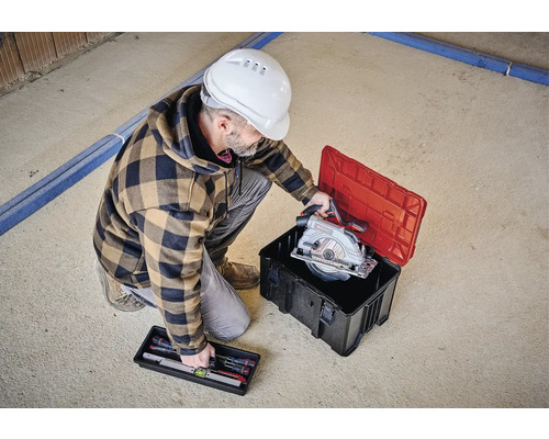 Artisan avec scie circulaire dans une caisse à outils et niveau à bulle dans un coffret