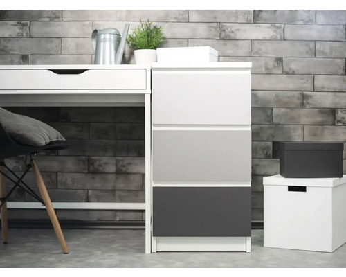 Scène avec bureau, élément à tiroirs et boîtes de rangement devant un mur de briques