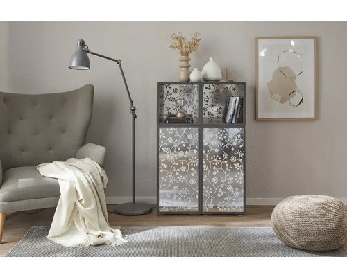 Scène de salon avec fauteuil, lampadaire, tapis, tabouret et étagère à motif floral