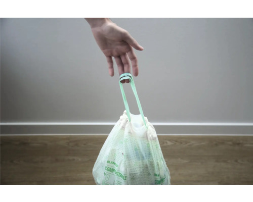 Une main tient un sac poubelle pour déchets organiques