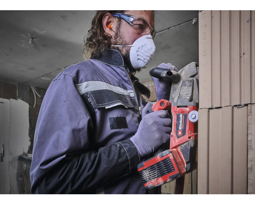Mann mit Atemschutzmaske und Schutzbrille arbeitet mit einer Mauernutfräse von Einhell an einer Wand.