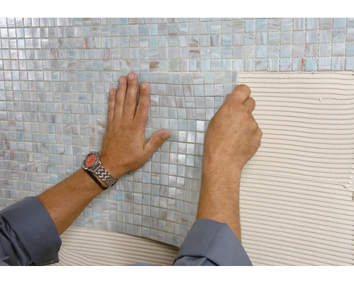 Pose de carreaux de mosaïque sur un mur