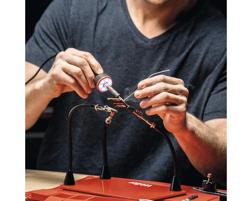 Une personne soude avec une station de soudage sur un plan de travail.