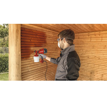 Mann sprüht Holz mit einer Farbspritzpistole
