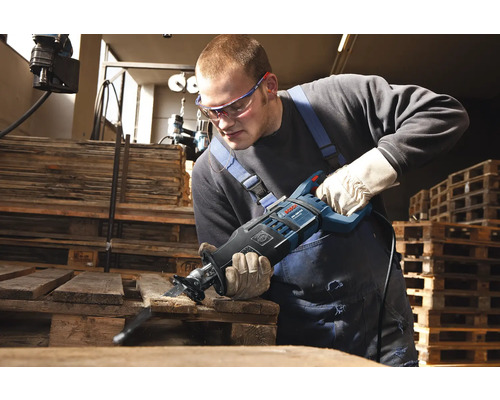 Ein Mann sägt mit einer Säbelsäge ein Holzbrett.