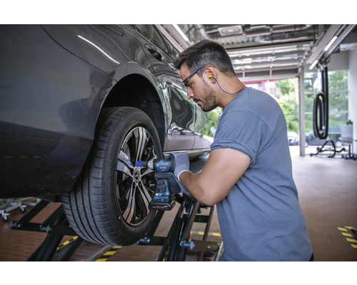 Un mécanicien change une roue avec une clé à choc à batterie.