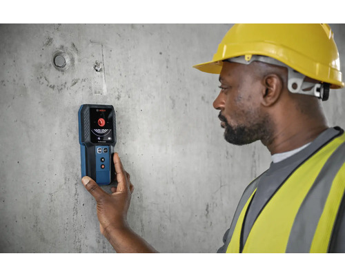 Ein Bauarbeiter verwendet ein Ortungsgerät von Bosch an einer Betonwand