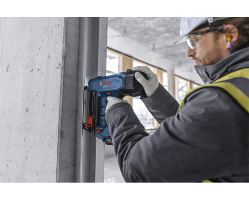 Un ouvrier utilise un pistolet de scellement sur un chantier.