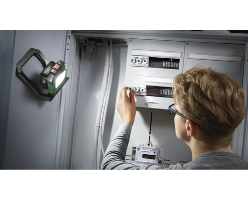 Électricien travaillant sur un boîtier à fusibles avec une lampe de travail à LED