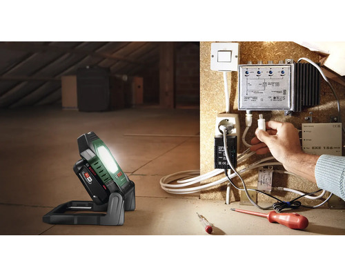 Scène dans les combles avec projecteur de chantier sans fil et installations électriques