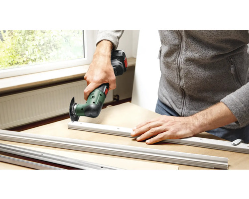 Un homme travaille avec un outil multifonctionnel sur des profilés en aluminium