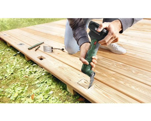 Outil multifonctionnel à batterie en cours d'utilisation sur une terrasse en bois.