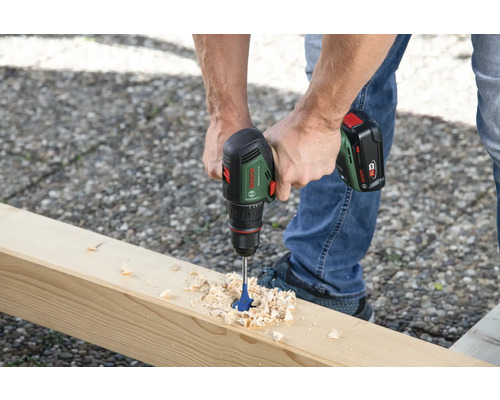 Une personne perce une planche de bois avec une perceuse-visseuse sans fil