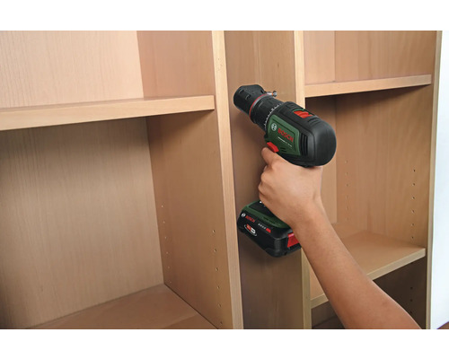 Une personne monte une étagère avec une visseuse sans fil.