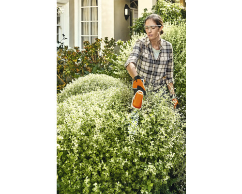 Femme taillant une haie avec un taille-haie dans le jardin