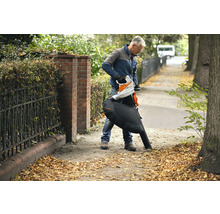 Ein Mann benutzt einen STIHL Akku-Laubsauger, um Laub zu entfernen.