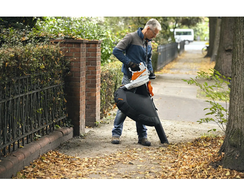 Ein Mann benutzt einen STIHL Akku-Laubsauger, um Laub zu entfernen.