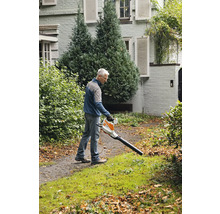 Ein Mann benutzt einen Laubbläser im Garten, um Blätter zu entfernen.