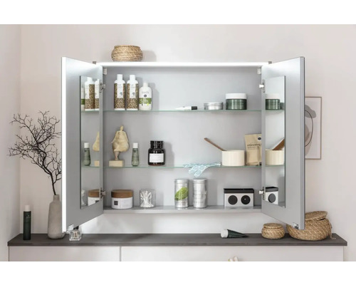 Armoire de toilette ouverte avec étagères en verre et divers articles de salle de bain