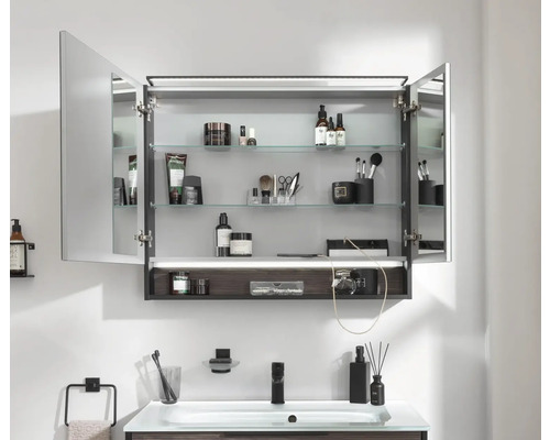 Armoire de toilette ouverte avec étagères en verre dans une salle de bains