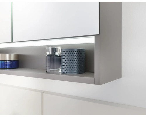 Detailansicht eines Spiegelschranks mit offenem Regal und Kosmetikprodukten