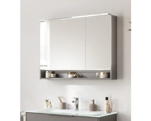 Spiegelschrank mit Beleuchtung und Ablage über einem Waschbecken im Badezimmer.