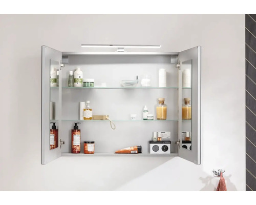 Armoire de toilette ouverte avec étagères en verre et divers articles de salle de bain