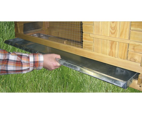 Une personne tire un bac à excréments d''une étable.