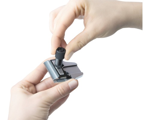 Une personne ajuste le jeu de coupe d''une tondeuse à cheveux.