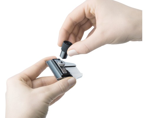 Une personne fixe un embout sur une tondeuse à cheveux.