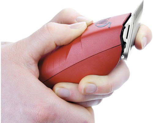 Une main tient une tondeuse à cheveux rouge.