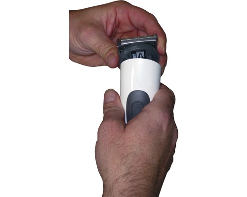 Les mains fixent la tête de coupe sur une tondeuse à cheveux