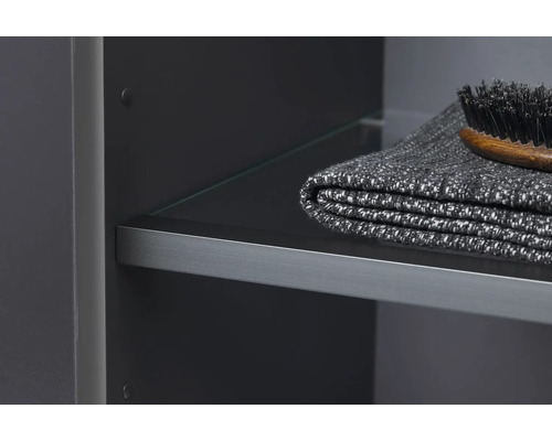 Vue détaillée d''un meuble de salle de bains avec étagère en verre, serviette et brosse