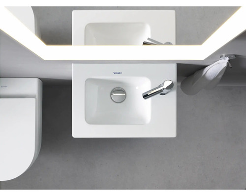 Vue de dessus d''une salle de bains avec lavabo, miroir avec éclairage, serviette et toilettes.