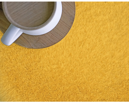 Detailansicht eines gelben Teppichs mit einer Tasse auf einem Untersetzer