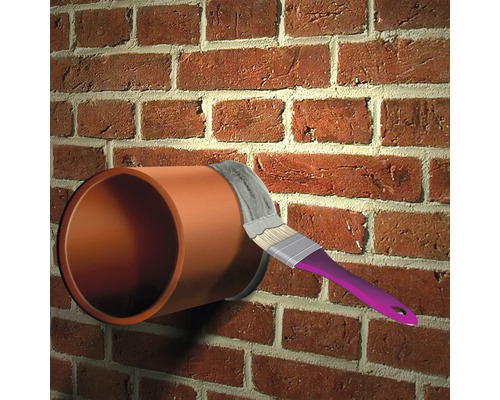 Ein Kunststoffrohr wird mit einem Pinsel an einer Ziegelwand abgedichtet.