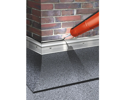 Étanchéification d''une plinthe avec du mastic devant un mur en briques