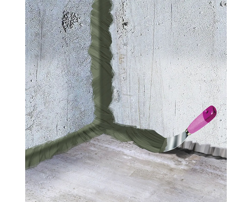 Le coin entre le mur et le sol est scellé avec du mastic, spatule à manche en bois