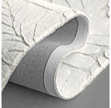 Tapis blanc à motif de feuilles, présenté enroulé