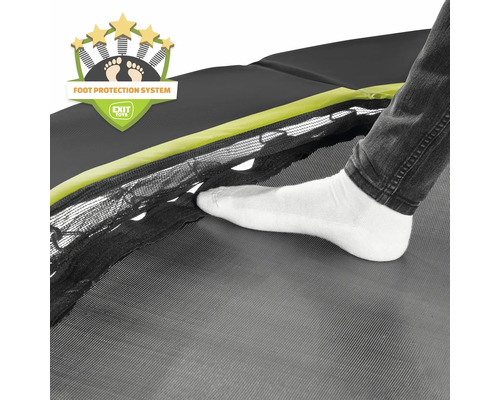 Vue détaillée d''un trampoline avec système de protection des pieds et un pied en chaussette blanche sur la toile de saut.