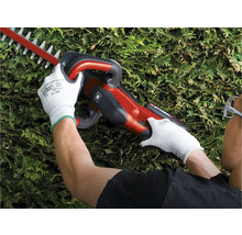 Eine Person benutzt eine Heckenschere, während sie Schutzhandschuhe trägt.