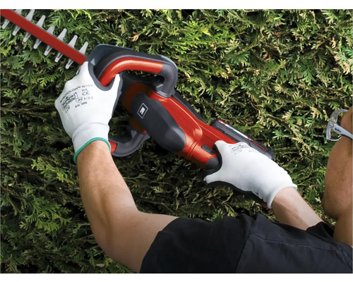 Eine Person benutzt eine Heckenschere, während sie Schutzhandschuhe trägt.