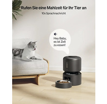 Automatische Futterausgabe für Haustiere neben einer Katze auf einem Sofa