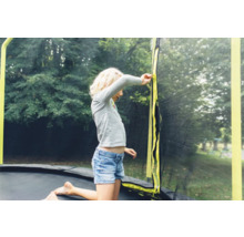 Fille sur un trampoline de jardin avec filet de sécurité