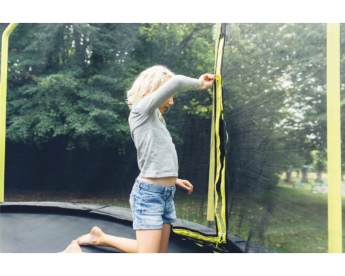 Fille sur un trampoline de jardin avec filet de sécurité