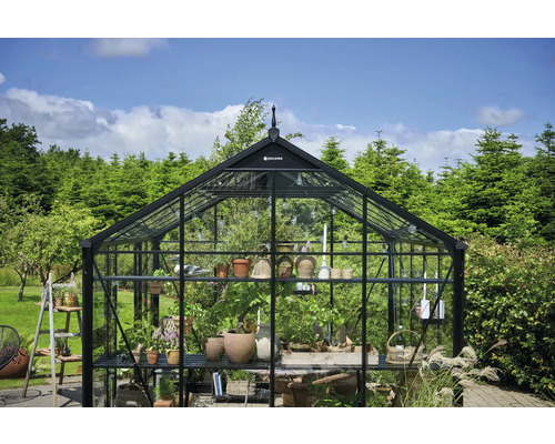 Gewächshaus mit Pflanzen und Gartenutensilien im Freien