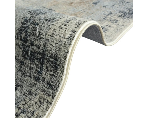 Vue détaillée d''un tapis avec motif abstrait et bords surjetés.