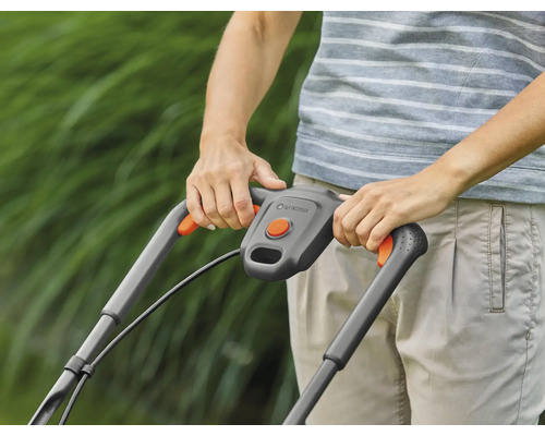 Person bedient Rasenmäher im Garten.