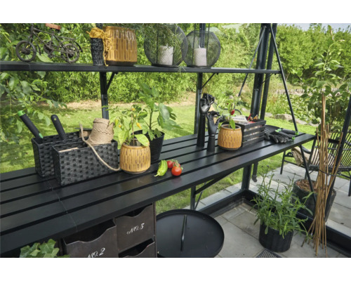 Serre avec étagères et accessoires de jardin tels que pots, plantes et outils.